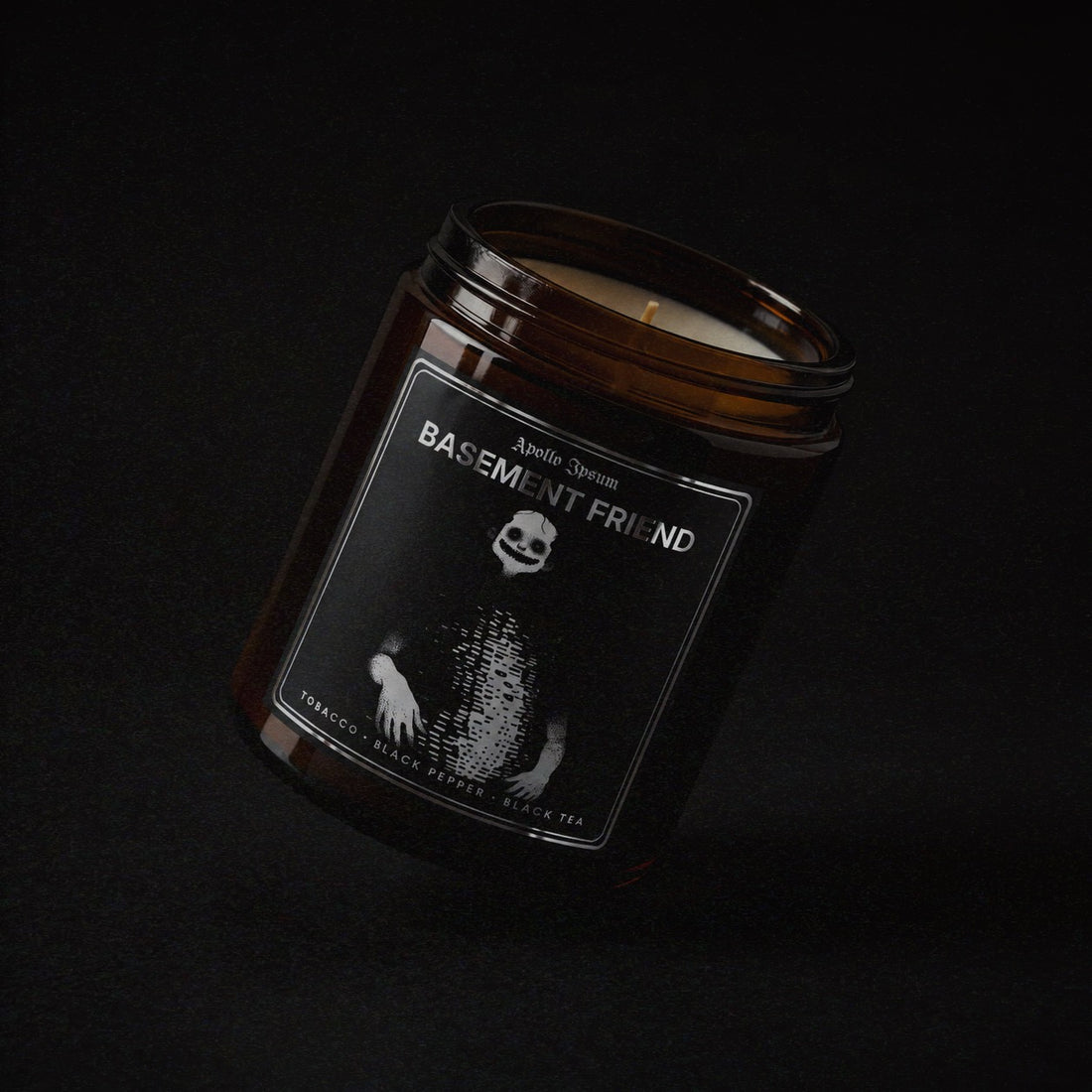 Basement Friend soy wax candle in an amber jar with illustrated label, Apollo Ipsum Things That Shouldn&
