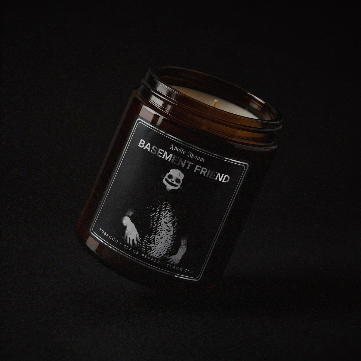 Basement Friend soy wax candle in an amber jar with illustrated label, Apollo Ipsum Things That Shouldn&