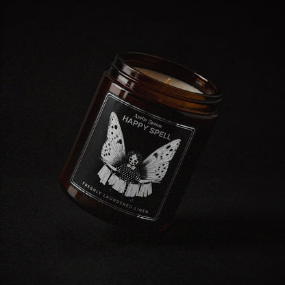 Happy Spell soy wax candle in an amber jar with illustrated label, Apollo Ipsum Things That Shouldn&