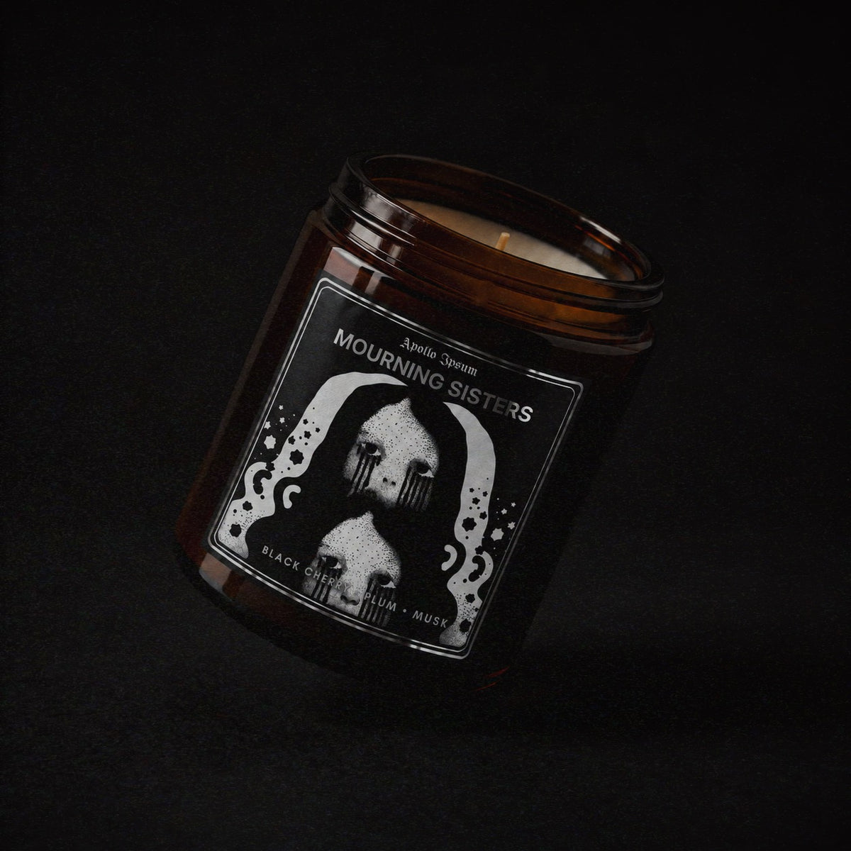 Mourning Sisters soy wax candle in an amber jar with illustrated label, Apollo Ipsum Things That Shouldn&