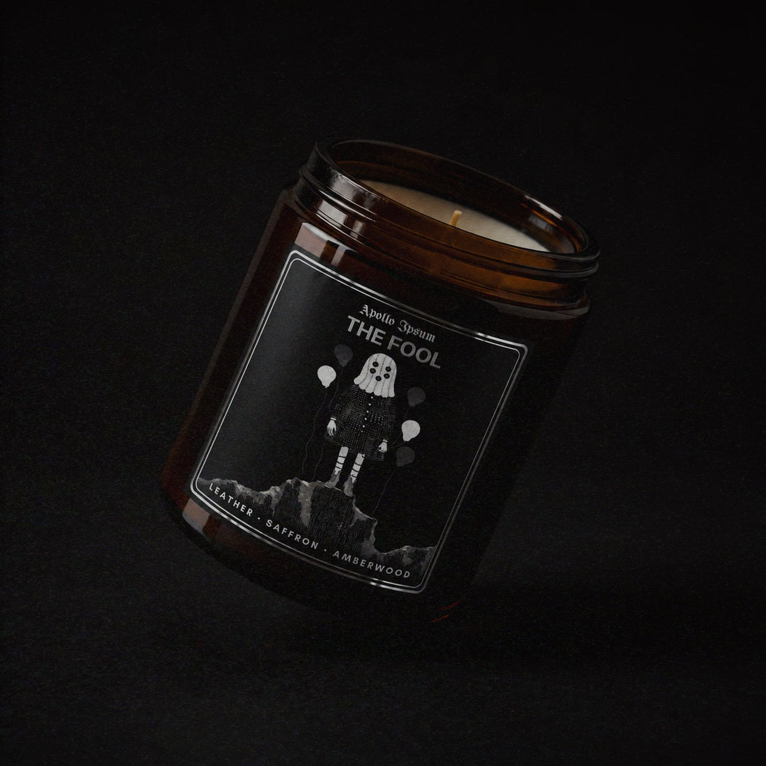 The Fool soy wax candle in an amber jar with illustrated label, Apollo Ipsum Things That Shouldn&
